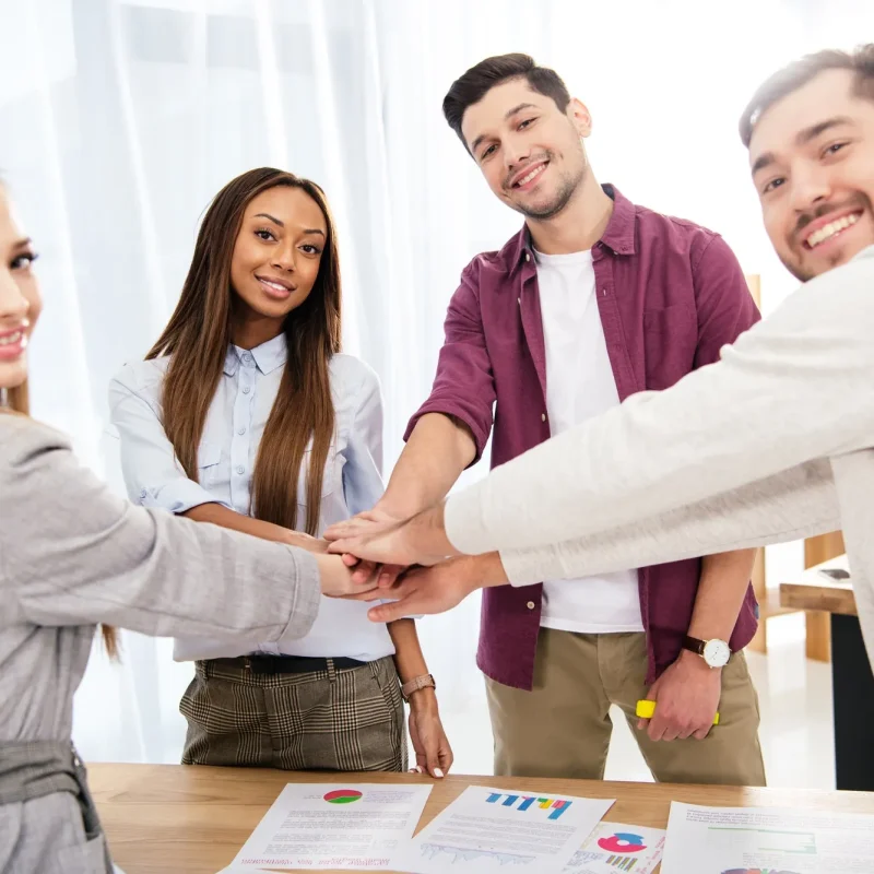 multicultural-group-of-marketing-managers-holding-hands-together-in-office-teamwork-concept